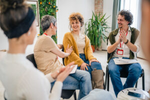 A group of people in recovery sitting in a circle with two addiction therapists 